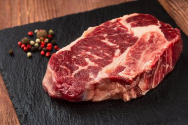 Taş tahtada taze çiğ ana Angus bifteği Striploin, Rib Eye. Karanlık bir ahşap arka planda