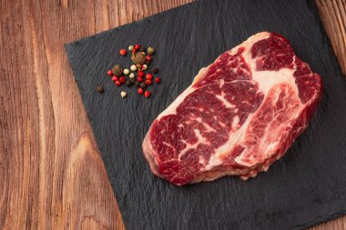 Taş tahtada taze çiğ ana Angus bifteği Striploin, Rib Eye. Üst Manzara. Karanlık bir ahşap arka planda