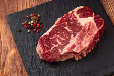 Taş tahtada taze çiğ ana Angus bifteği Striploin, Rib Eye. Üst Manzara. Karanlık bir ahşap arka planda