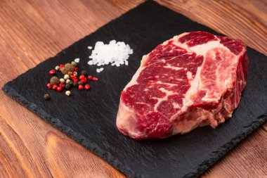 Taş tahtada taze çiğ ana Angus bifteği Striploin, Rib Eye. Üst Manzara. Karanlık bir ahşap arka planda