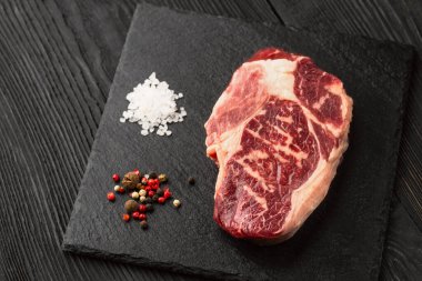 Taş tahtada taze çiğ ana Angus bifteği Striploin, Rib Eye. Üst Manzara. Karanlık bir arka planda