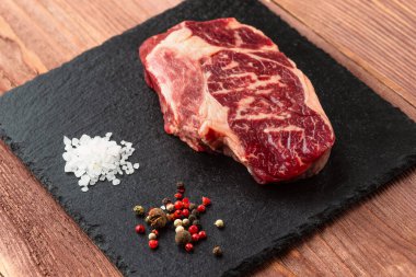 Taş tahtada taze çiğ ana Angus bifteği Striploin, Rib Eye. Üst Manzara. Karanlık bir ahşap arka planda