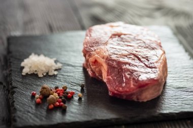 Taş tahtada taze çiğ ana Angus bifteği Striploin, Rib Eye. Karanlık bir arka planda