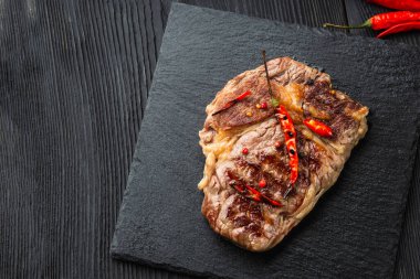Biftek ve kırmızı biber tahtada siyah ahşap masada. Üst görünüm.