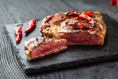 Kırmızı biber ve baharatlı, orta pişmiş ızgara biftek, koyu kırsal ahşap arka plan, üst manzara, yazı için yer.