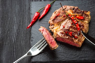 Kırmızı biber ve baharatlı, orta pişmiş ızgara biftek, koyu kırsal ahşap arka plan, üst manzara, yazı için yer.