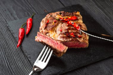 Kırmızı biber ve baharatlı, orta pişmiş ızgara biftek, koyu kırsal ahşap arka plan, üst manzara, yazı için yer.
