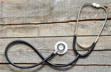 Siyah stetoskop. Ahşap arka plan üzerinde siyah stetoskop.