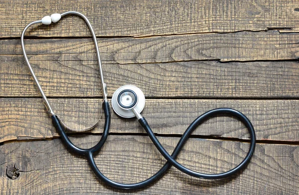 Siyah stetoskop. Ahşap arka plan üzerinde siyah stetoskop.