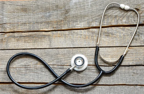 Siyah stetoskop. Ahşap arka plan üzerinde siyah stetoskop.