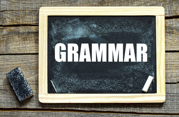 GRAMMAR handwritten with white chalk on a blackboard on wood background