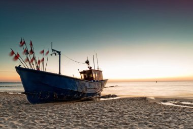 Gün batımında Baltık sahilde balıkçı teknesi