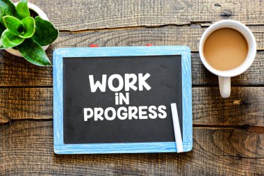 İş Prograess bir yazı tahtası ahşap arka plan üzerinde beyaz tebeşir ile el yazısı