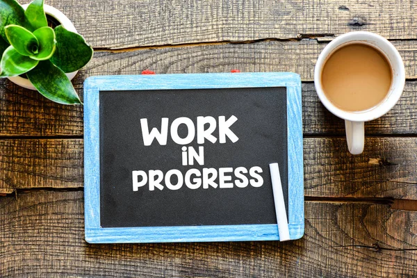 İş Prograess bir yazı tahtası ahşap arka plan üzerinde beyaz tebeşir ile el yazısı