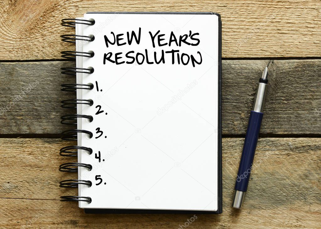 New year's resolution on a notebook, wooden background 