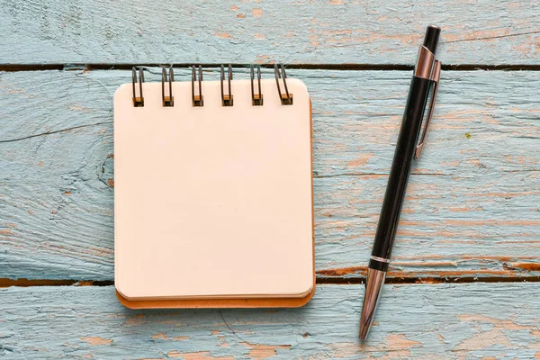 ahşap arka planda boş not defteri ve kalem, üst görünüm 