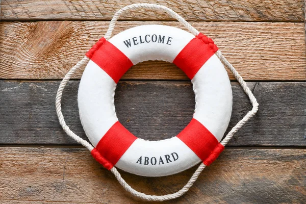 Lifebuoy with Welcome aboard phrase on wooden background