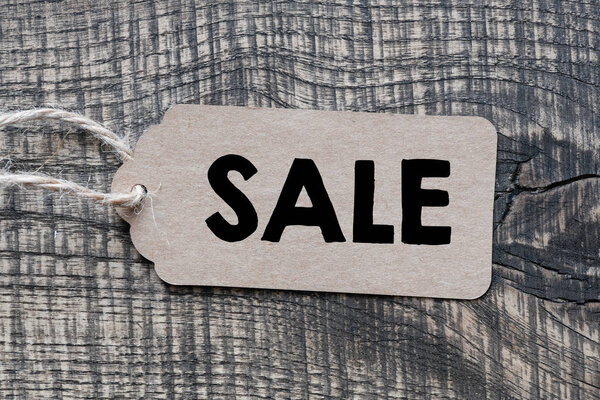 sale text on tag on wooden  background 