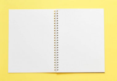 sarı arka plan üzerinde boş not defteri ile çalışma yeri üst görünümü 