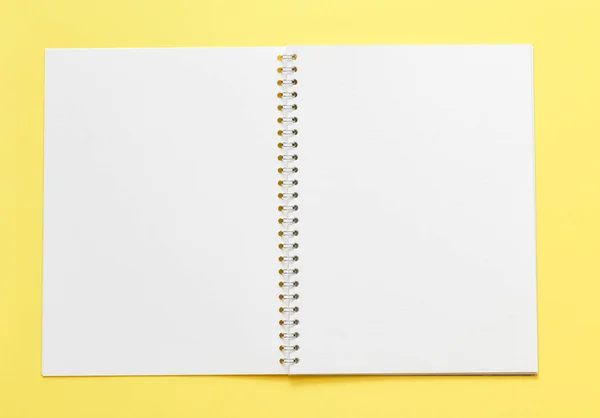 黄色の背景に空のメモ帳を持つ作業場所の上部図 — ストック写真