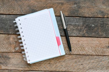 ahşap masa yüzeyinde kağıt ders kitabı, spiral defter ve kalem