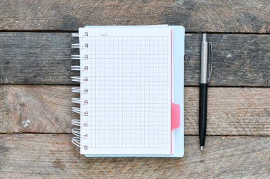 ahşap masa yüzeyinde kağıt ders kitabı, spiral defter ve kalem