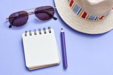 Güneş gözlüğü ile Hasır şapka, büyüteç, kalem, masada not defteri.