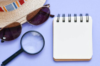 Güneş gözlüğü ile Hasır şapka, büyüteç, masada not defteri.