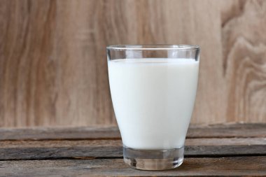 Tahta arka planda bir bardak süt