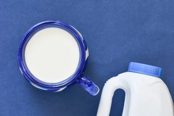 Blue cup of milk with bottle on blue background