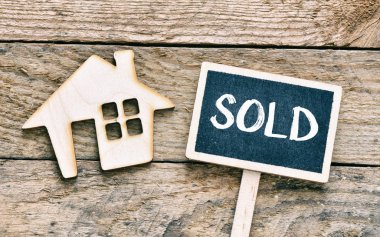 Satılan plaka ile ahşap arka plan üzerinde küçük bir ev