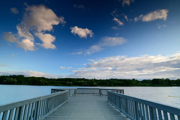 地平線上の森と空の木製の桟橋と美しい湖 — ストック写真