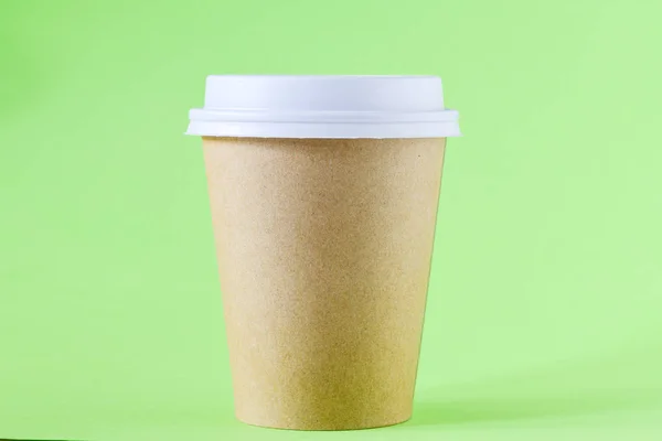 close-up view of brown paper cup with coffee to go on green background