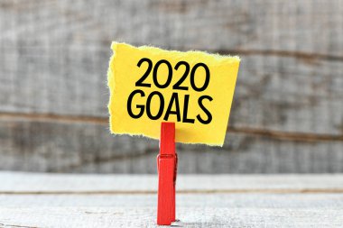 Motivasyon 2020 gol yazıt ahşap arka plan üzerinde kırmızı ahşap clothespin ile sarı kağıt üzerinde 