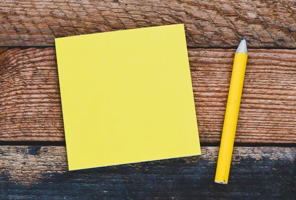 木製のテーブルの上に空白の黄色のメモカードと黄色の鉛筆 音符または挿入グラフィックスを入力する空白スペース — ストック写真