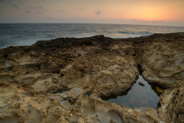 Turkuvaz suları, kumlu bir plaj, kayalık kıyı şeridi ve açık mavi gökyüzü içeren nefes kesici Kıbrıs Akdeniz manzarası. Yaz tatilleri, turizm ve doğa aşıkları için mükemmel bir tatil yeri..