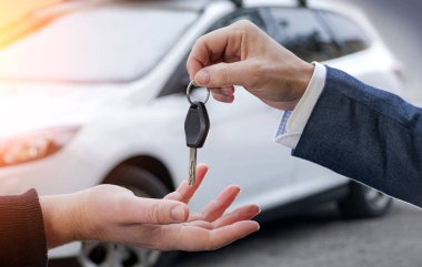 Arabanın anahtarlarını araba ile arka planda tutan erkek 