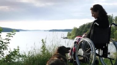 Köpekli tekerlekli sandalyedeki kadın.