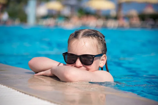 Güneş gözlüklü bir beyaz kız mavi bir havuzdan tarar