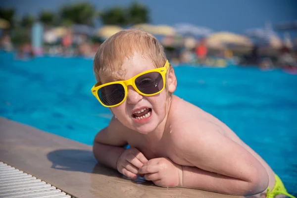 Güneş gözlüklü bir beyaz kız mavi bir havuzdan tarar