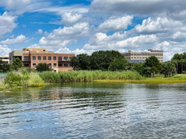 Pensacola, Florida 'daki barışçıl göl manzarasında, yemyeşil çimen ve ağaçların arkasındaki iki çok katlı bina yer alıyor..