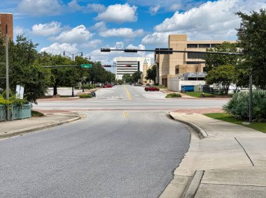 Pensacola, Florida 'da sakin bir şehir kavşağında ticari binalar ve gölgeli kaldırımlarla kaplı çok şeritli yollar yer alıyor..
