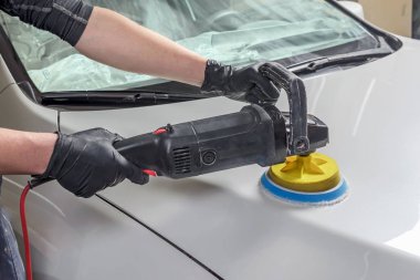 Adam elinde bir Parlatıcı tutar ve araba parlatır