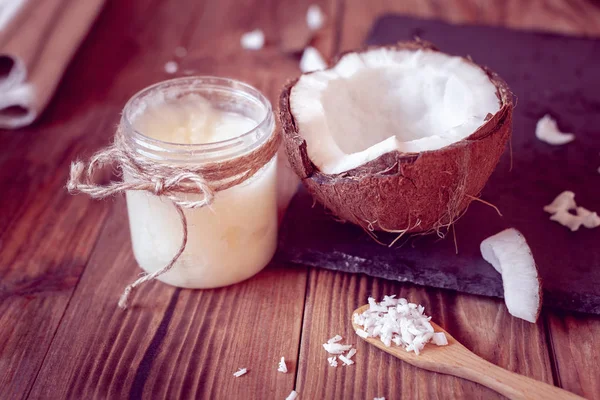 Helft Van Kokosnoot Kokosolie Een Fles Een Houten Achtergrond — Stockfoto
