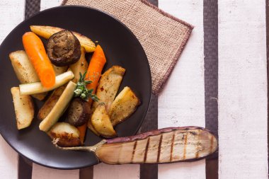 Beyaz çizgili arka planda çeşitli sebze ile siyah plaka