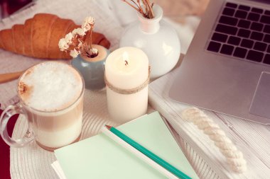 laptop ve defter kalem bir tablo ile ve kruvasan ile kahve