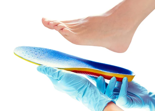 Hands in rubber gloves hold an orthopedic insole