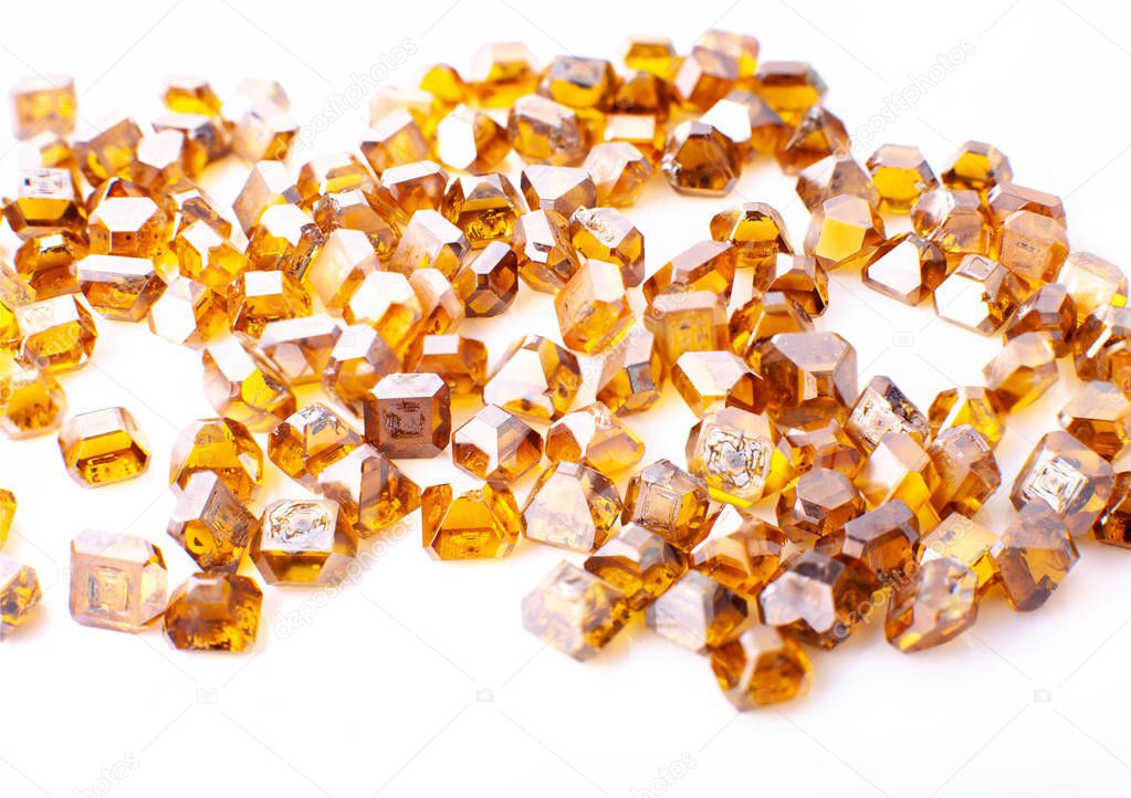 the scattered yellow synthetic diamonds in macro on a white background