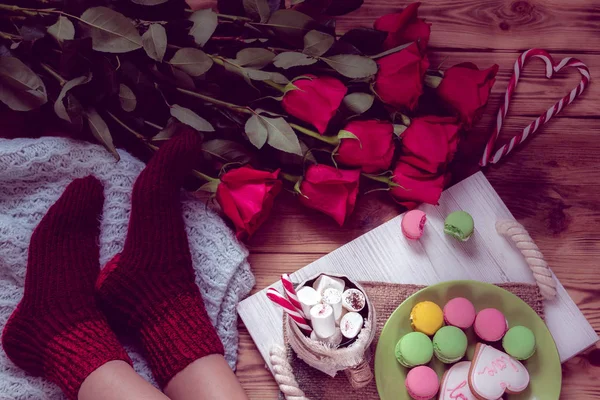 女性脚ソックス 赤いバラとストライプ ロリポップの心と盆にコーヒー マシュマロ マカロン ジンジャーブレッド クッキーのカップで朝食 聖バレンタインの日のためのある静物 — ストック写真