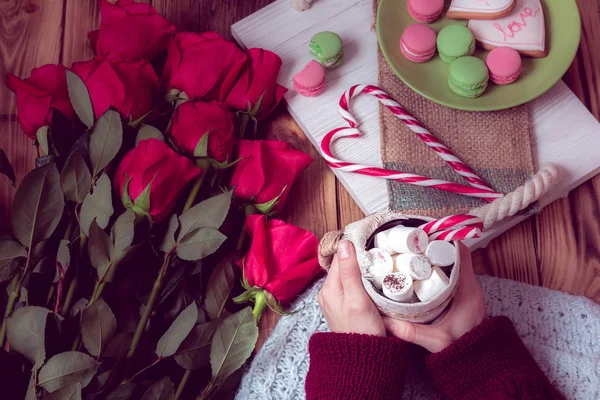 ストライプ ロリポップの心を持ったコーヒーそして真っ赤なバラで女性の手 聖バレンタインの日のためのある静物 — ストック写真